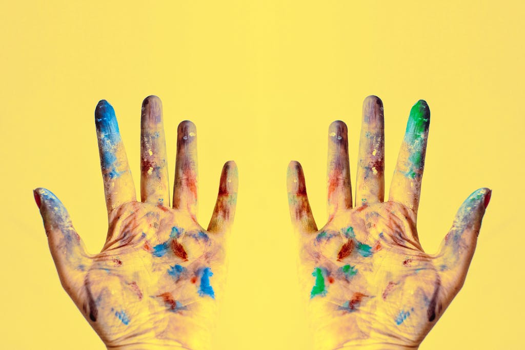 Colorful fingers spread against a bright yellow backdrop, showcasing creativity.